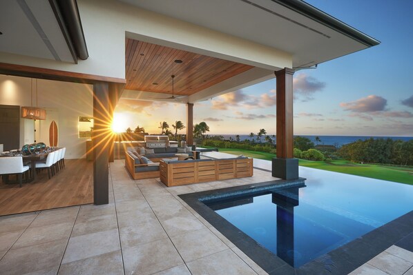 Enjoy the modern outdoor lanai with sunset views, an infinity pool, and a cozy seating area.