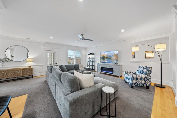 Spacious & comfy living room with large sectional, recliner, 75" TV & fireplace.