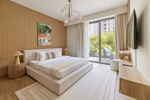King bed, TV, balcony chairs, and garden view