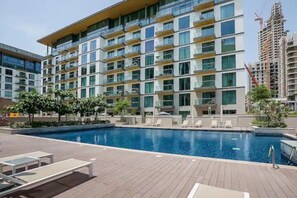 Outdoor swimming pool with lounge chairs and apartment building view