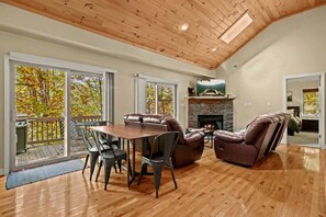 Step into a welcoming living space with plush sofas, a warm fireplace, a smart TV, and access to a charming back deck.
