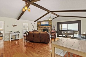 The living room seamlessly connects to a wrap-around deck and outdoor living space, offering an ideal vantage point for enjoying stunning sunsets or unwinding with a captivating book.