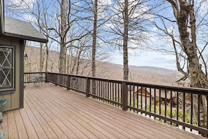 The living room seamlessly connects to a wrap-around deck and outdoor living space, offering an ideal vantage point for enjoying stunning sunsets or unwinding with a captivating book.