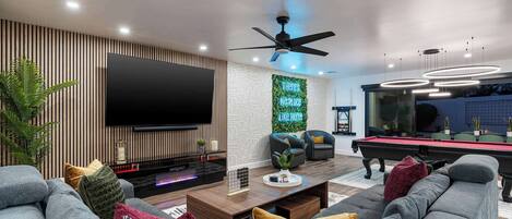 A cozy den with a large TV, a comfortable sofa, and a pool table, creating the perfect space for relaxation and entertainment.