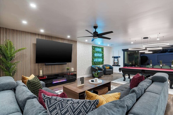 A cozy den with a large TV, a comfortable sofa, and a pool table, creating the perfect space for relaxation and entertainment.




