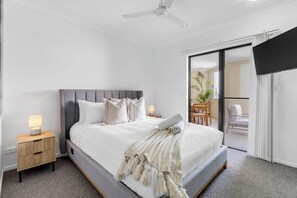 Retreat to the primary bedroom featuring a plush king bed, TV, private ensuite, and direct balcony access.
