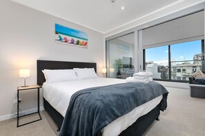 The Queen bedroom has a glass sliding door that separates it from the open-plan living area.