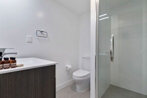 The bathroom has a toilet, vanity and shower.