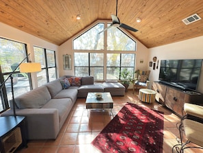 Vaulted living room, door to deck, sofa, coffee table, Smart TV ceiling fan