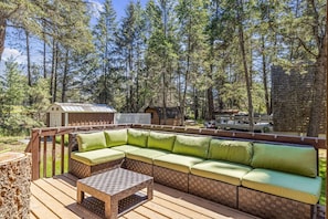 The Hilltop Hive's backyard with a large deck space, outdoor seating, a BBQ & dedicated fire pit area.
