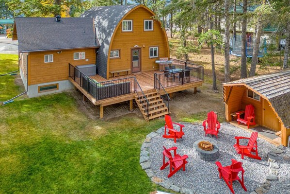 The Hilltop Hive's backyard with a large deck space, outdoor seating, a BBQ & dedicated fire pit area.