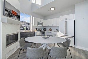 Modern kitchen and dining area with a fireplace and mountain views.