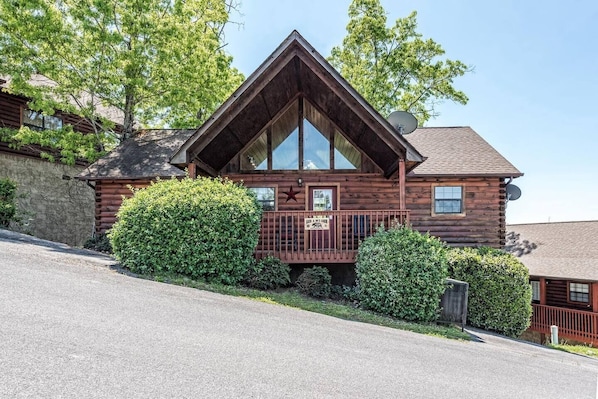 Feel the peace and charm of summer at this inviting log cabin as you take in the lush greenery and mountain air from the cozy front porch. Imagine yourself unwinding in this serene retreat, surrounded by nature's tranquility.