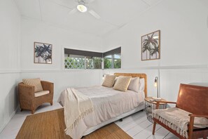 The second bedroom is comfortably furnished with a queen-size bed, side tables, reading lamps, two cosy armchairs and a ceiling fan.