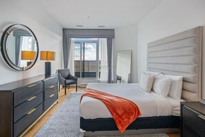 Primary bedroom with a queen bed, access to the balcony, walk-in closet & a private ensuite full bathroom.