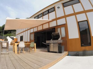 ・[Dome Tent B/Exterior] A large parasol is set up on the wooden deck.