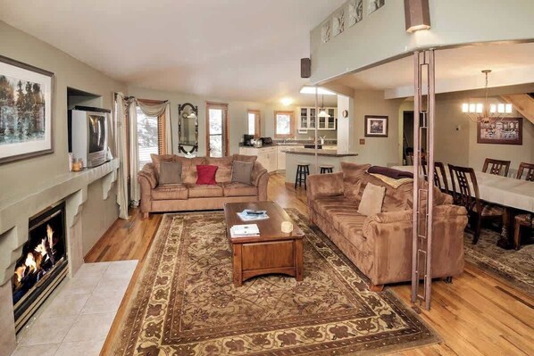 Large living room with flat-screen TV (not pictured) and gas fireplace. The center couch is a brand-new sleeper sofa.