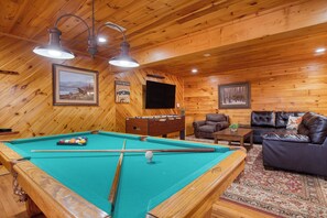 The lower-level game room features a foosball table, a Pacman arcade game, and a pool table.