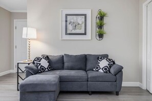 The living area has a sofa with a chaise as well as some other chairs for seating.