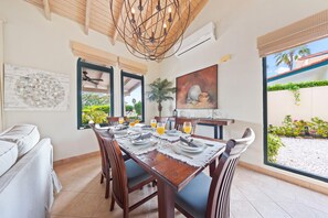 A spacious, elegant dining area with a rustic wooden table, comfortable chairs, and large windows that provide natural light and garden views, perfect for family gatherings.