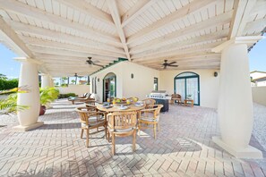A covered outdoor dining and seating area, ideal for al fresco meals and relaxation, complete with a grill.