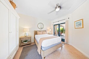 A cozy bedroom with soft lighting and elegant design, offering a serene ambiance enhanced by natural light and a view of the outdoor patio.