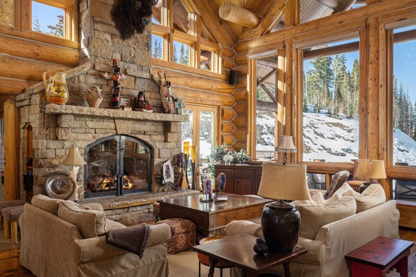 Main level sitting area with gas fireplace and large windows overlooking the Double Cabins ski run