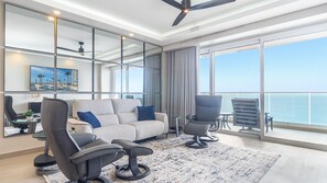 The living room with its mirrored wall, double sliding doors, push button sofa, and two reclining chairs along with a 75" wall mounted TV.