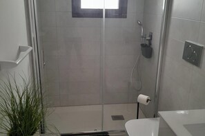 Bathroom with large walk-in shower, toilet & sink with vanity unit under.