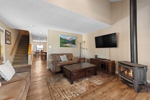 Living area with ample seating including a queen sleeper sofa, TV, fireplace, and balcony access.