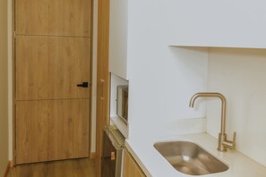 Cocina moderna equipada con lavaplatos de acero inoxidable, microondas y nevera.