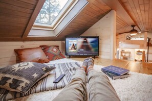 Comfy lounge loft TV area complete with smart TV, mini classic Nintendo system, and books.