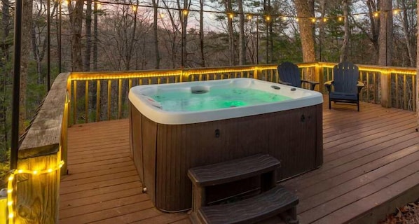 Your private forest retreat: a hot tub oasis illuminated by enchanting string lights.