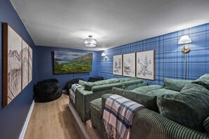 Welcome to our cozy home theater, where a large sectional sofa and bean bag chairs create the ultimate movie-watching experience against deep blue walls.