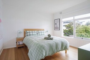 The thoughtfully furnished first bedroom features a queen-size bed with side tables and reading lamps.