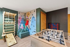 Playroom features a rock wall, swedish ladder, play couch, and foosball table