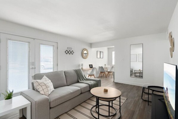 The living room’s plush seating beckons you to sink in and relax, surrounded by light and airy decor.