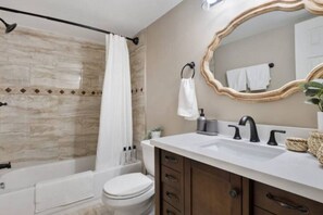 This bright and welcoming bathroom invites you to freshen up in comfort. Enjoy the forest-inspired shower curtain that adds a calming touch to your routine, complemented by the cozy rug underfoot and sparkling clean fixtures.