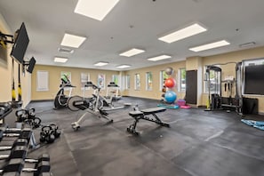 Spacious, well-lit gym equipped with a variety of cardio machines, free weights, and strength-training equipment.