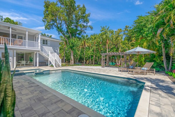 Pool view with tanning lounge chairs.  Stairs lead to second floor balcony.
