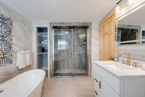 Unwind after a long day in this luxurious bathroom, complete with a tiled walk-in shower and a gorgeous clawfoot tub for a spa-like experience.
