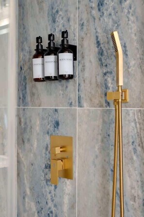 Freshen up in the beautifully tiled shower featuring a convenient handheld shower head and premium bath products: shampoo, conditioner, and body wash.