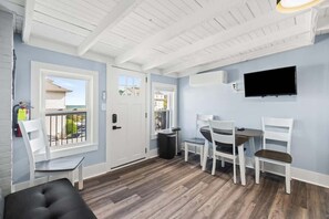 Cozy living area with a futon, smart TV, and dining table—perfect for relaxing or enjoying a meal after a day at the beach.