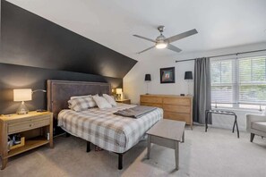 Unwind in the serene primary bedroom, featuring a king-size bed with premium linens, a stylish accent wall, and blackout curtains. Enjoy your favorite shows on the large TV in this comfortable retreat.