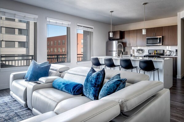 Beautifully designed living room. 75" TV, leather sofa and amazing views of mountains and city skyline.