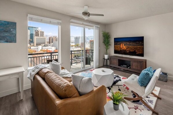 Beautifully designed living room. 75" TV, leather sleeper sofa and amazing views of mountains and city skyline.