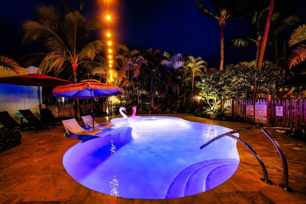 Bask in the glow of the illuminated pool, surrounded by lush greenery and warm lighting, offering the perfect setting for a serene night swim.