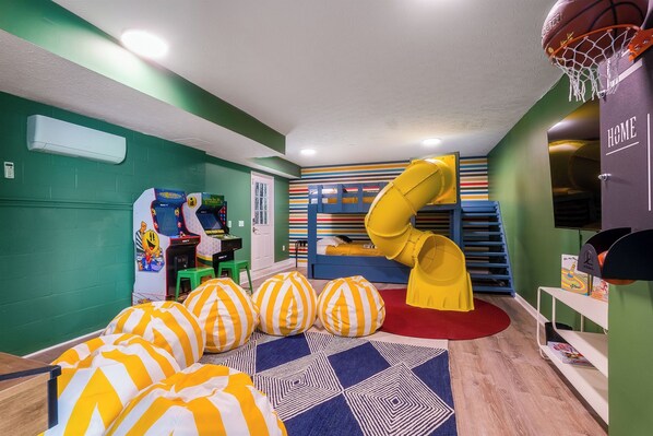 Children's bunk room with tube slide, arcade games, TV, childrens books, air hockey, bean bag chairs and lots of room to play