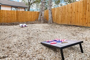 Backyard with cornhole set and plenty of space for your furry friends!