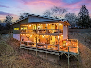 From the back, you’ll see two expansive decks designed for both relaxation and entertainment—one for alfresco dining and sunset views, the other for soaking in the hot tub, unwinding in the sauna, or gathering around the fire table.